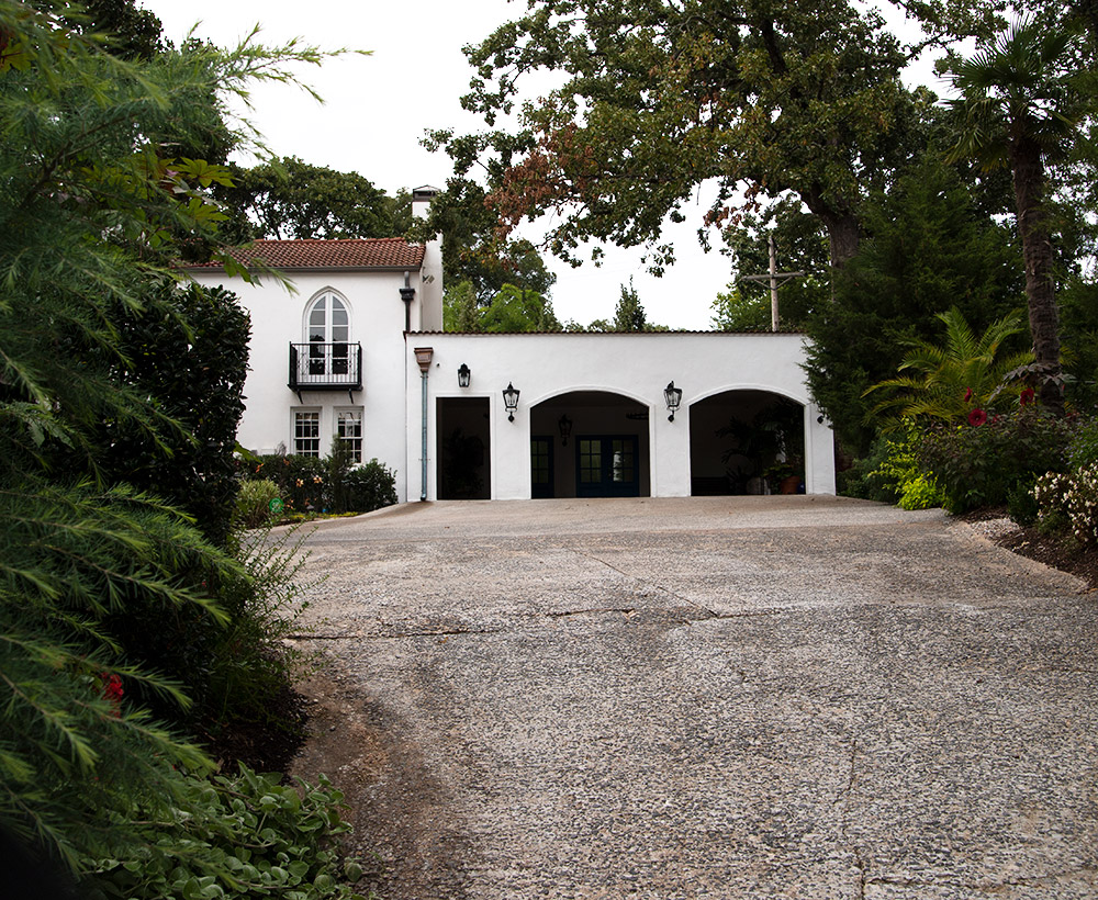 Driveway leading up to multistory white building with garage entrances