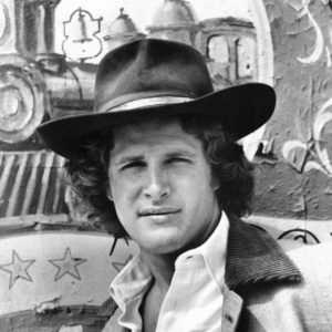 White man wearing cowboy hat and open collared shirt