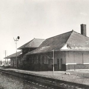 Single story brick building beside railroad tracks