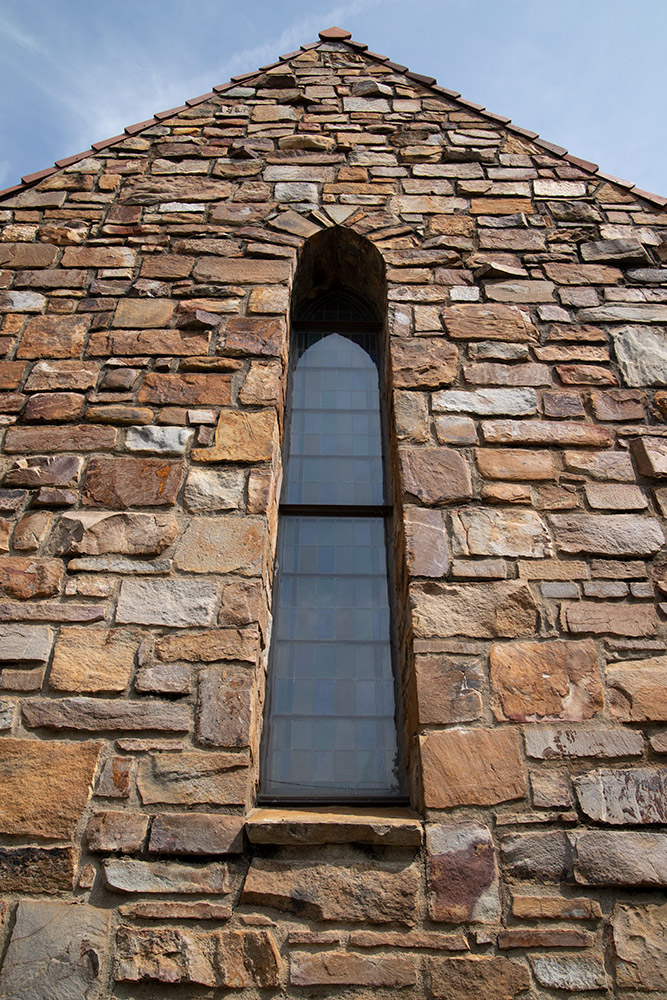 Narrow but tall window feature centered in stone church wall