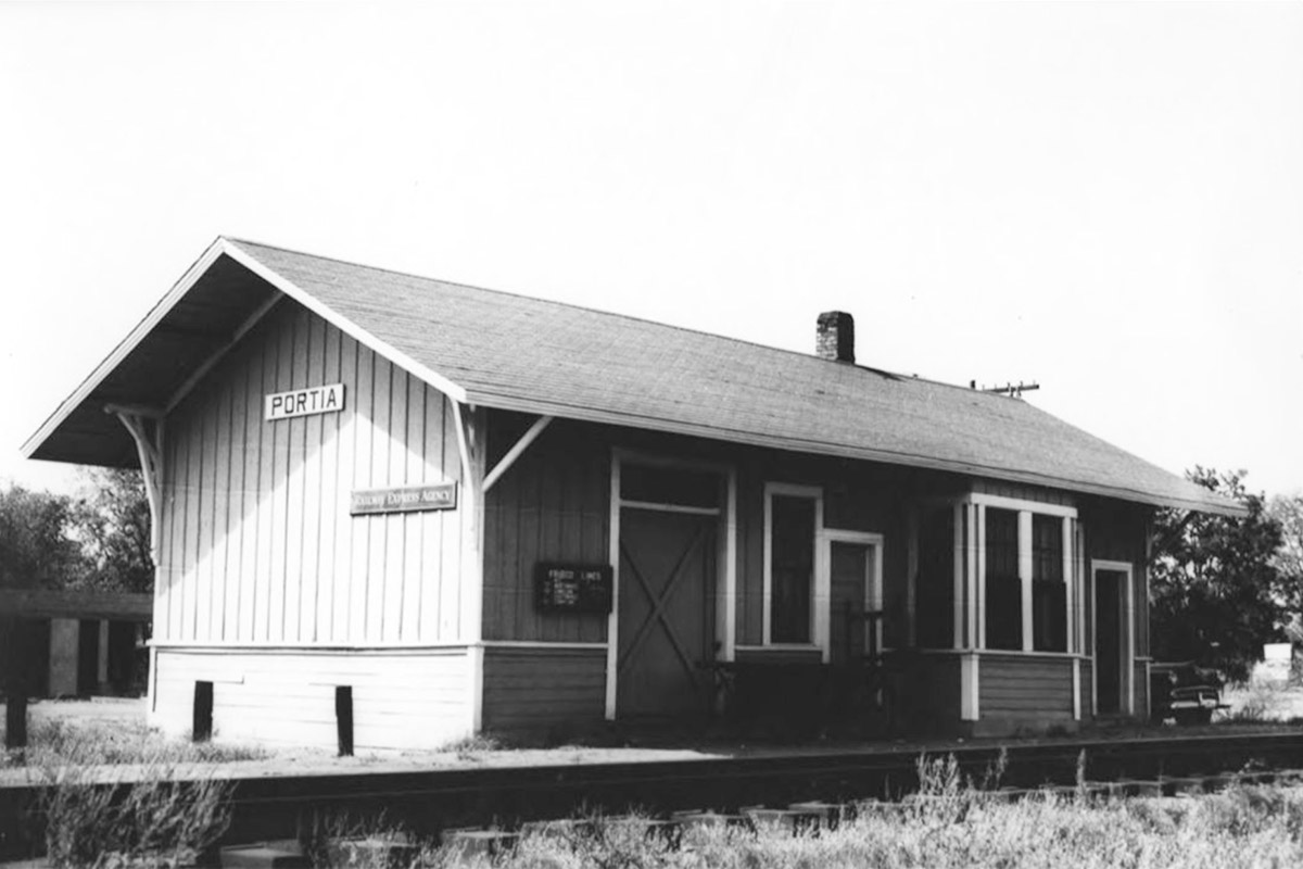 Single story wooden building beside railroad tracks