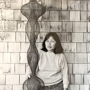 Asian woman standing next to wire sculpture