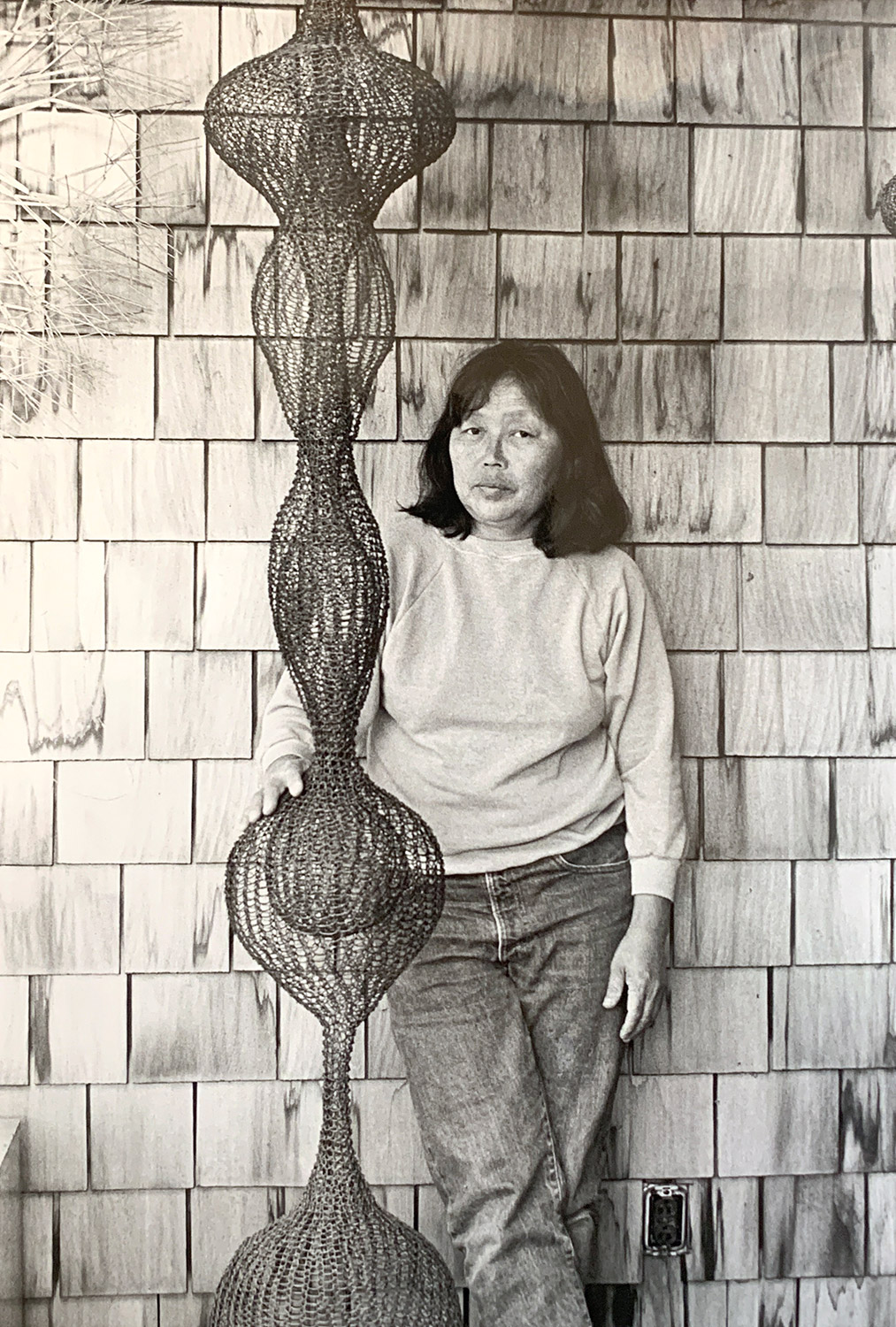 Asian woman standing next to wire sculpture