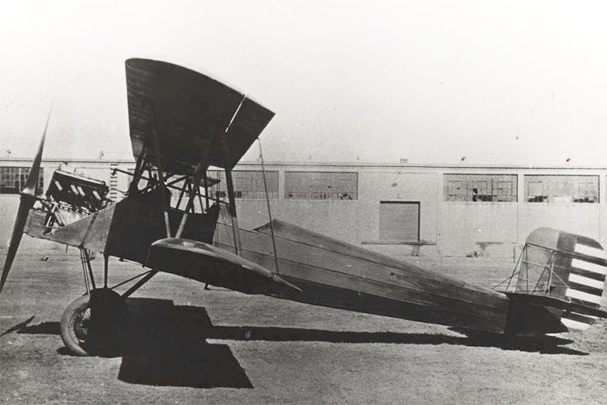 Biplane sitting in front of low building