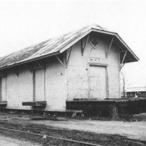 Single story wooden building beside railroad tracks