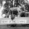 three white women on float decorated with flowers with "Pea Ridge Heart of the Ozarks" on the side