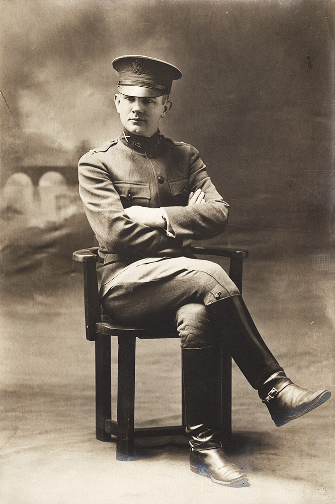 White man in military uniform sitting in chair with legs crossed