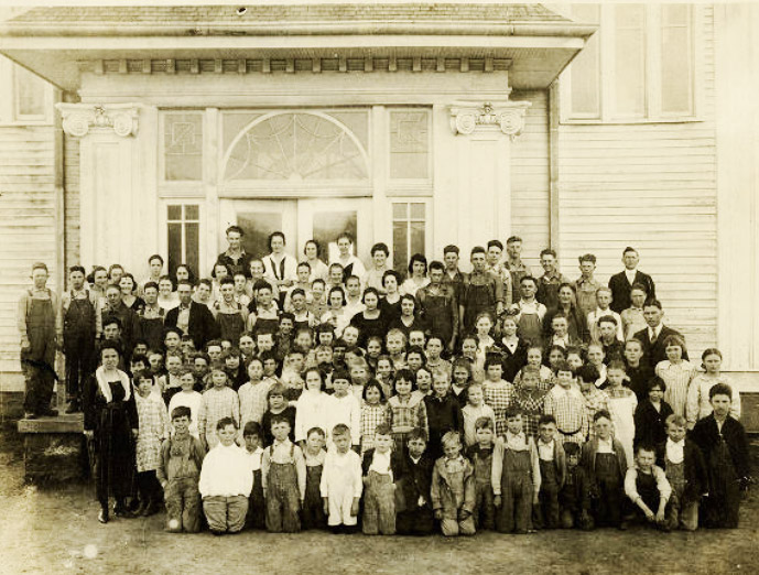 Large group of people in front of wooden building with arch window