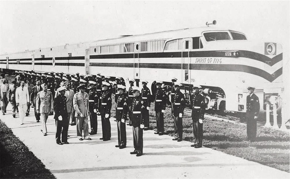 Large group of people in military garb standing in formation next to train