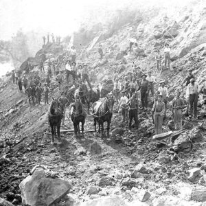 Men and horses working on side of rock strewn hill