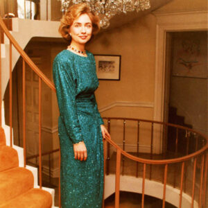 White woman on stairs in blue-green formal gown