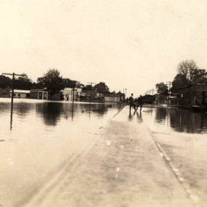 two men standing on railroad tracks surrounded by flood waters