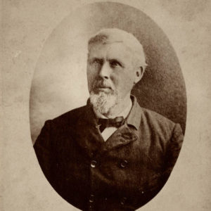 White man with white beard wearing suit and bow tie