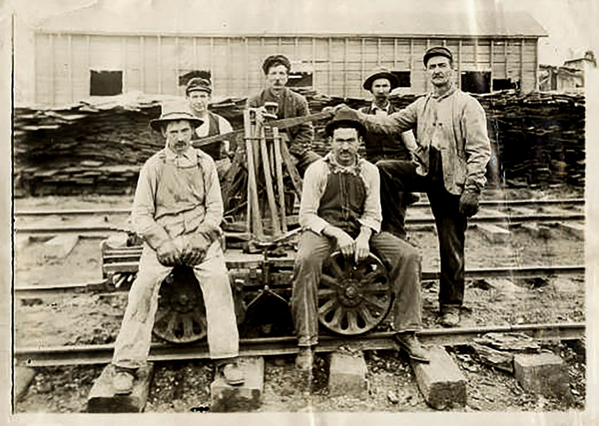White men seated on hand cart on railroad tracks
