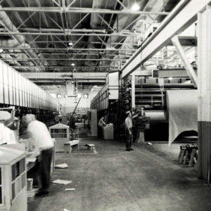 Men on floor of factory adjacent to huge machines