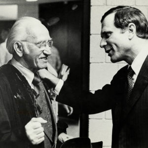 Two white men facing each other and smiling