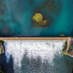 Overhead view of water flowing over dam