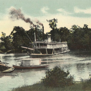 Steamboat on river with tree-lined shoreline in background