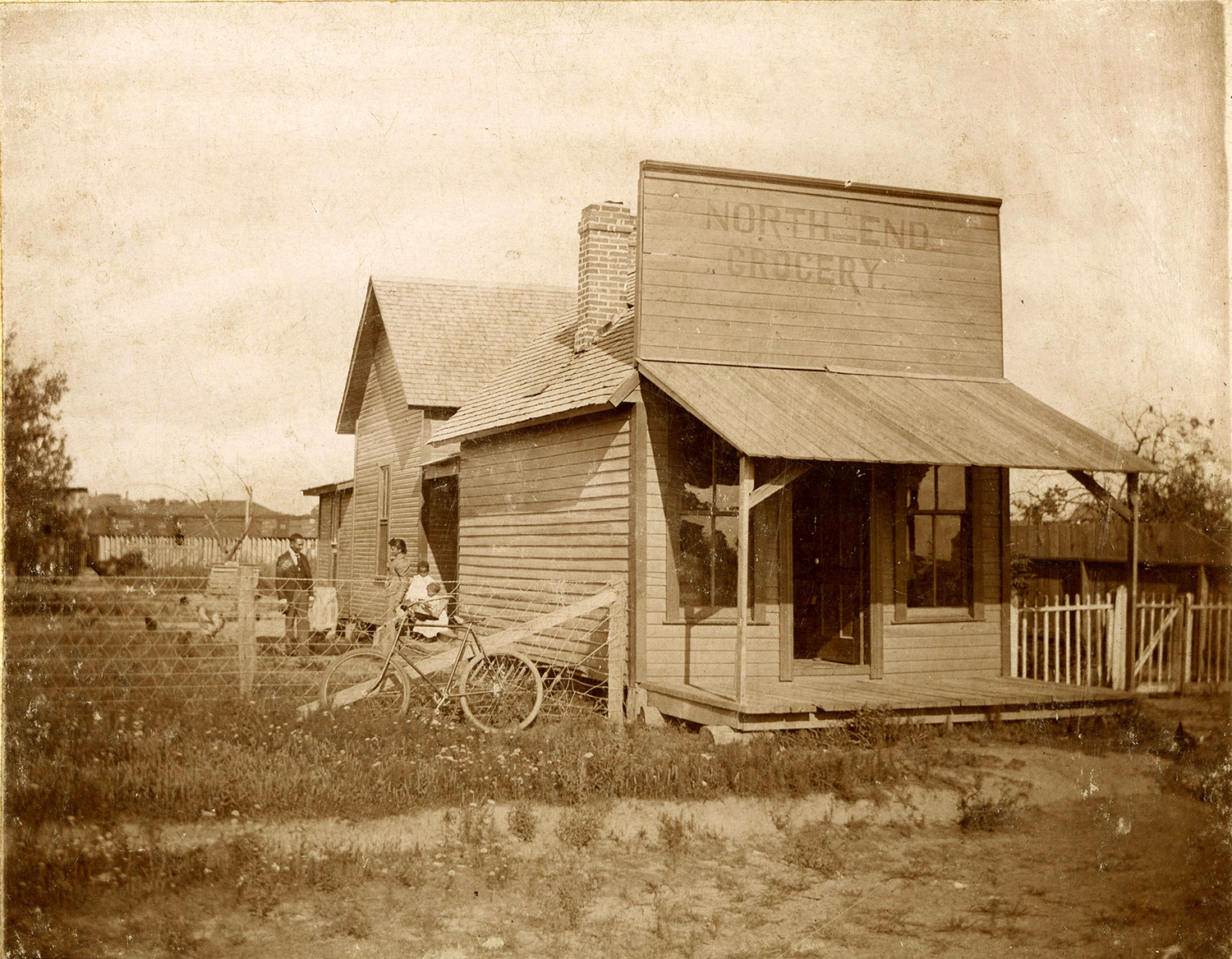 African American family standing beside wooden building