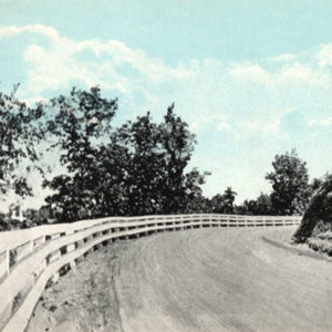 Roadway and fence curving to right around hill