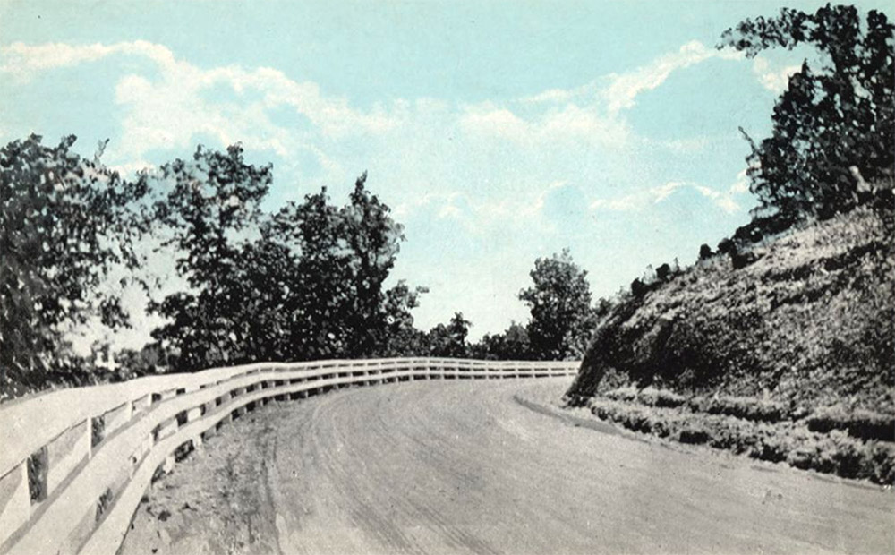 Roadway and fence curving to right around hill