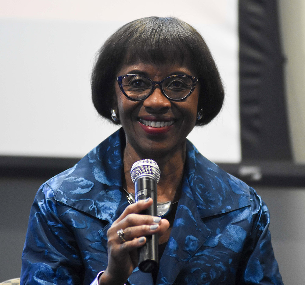 African American woman in blue dress speaking into microphone