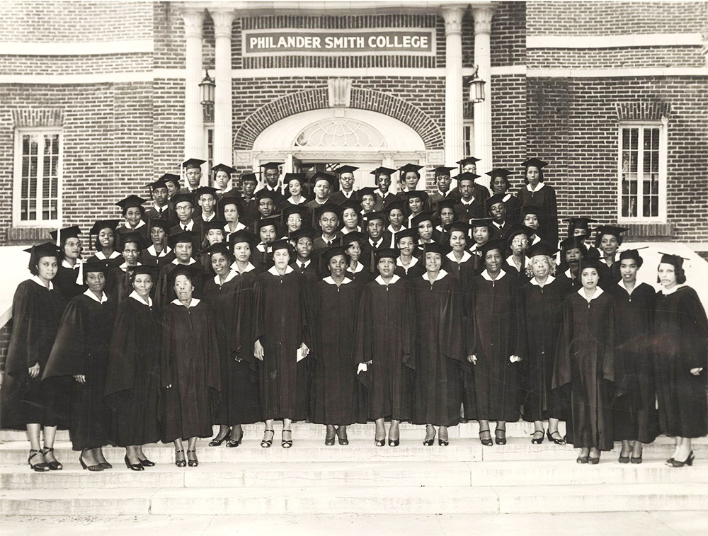 Large group of African Americans in cap and gown on steps of building with "Philander Smith College" on the front