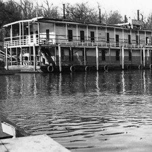 Two story wooden houseboat moored at riverbank
