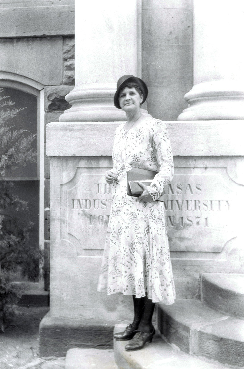 White woman in dress standing on concrete steps