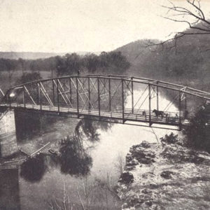 Horse and wagon crossing bridge across river