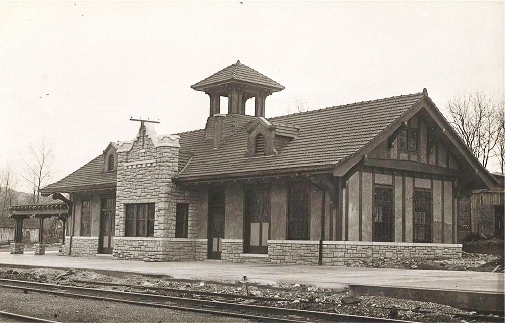 Rock building with bell tower like structure beside railroad tracks