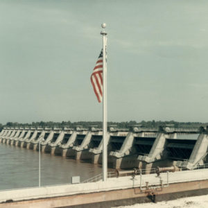 American flag over dam on river