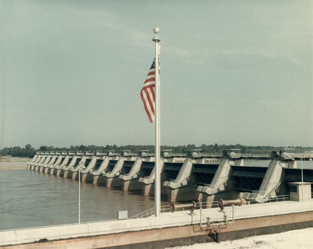 American flag over dam on river