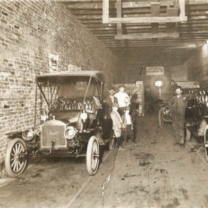 Three white men and two children in narrow building space with several cars