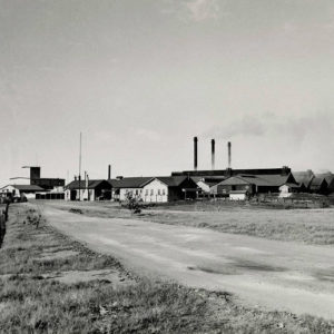 Factory buildings with smoke stacks emitting smoke and road in the foreground