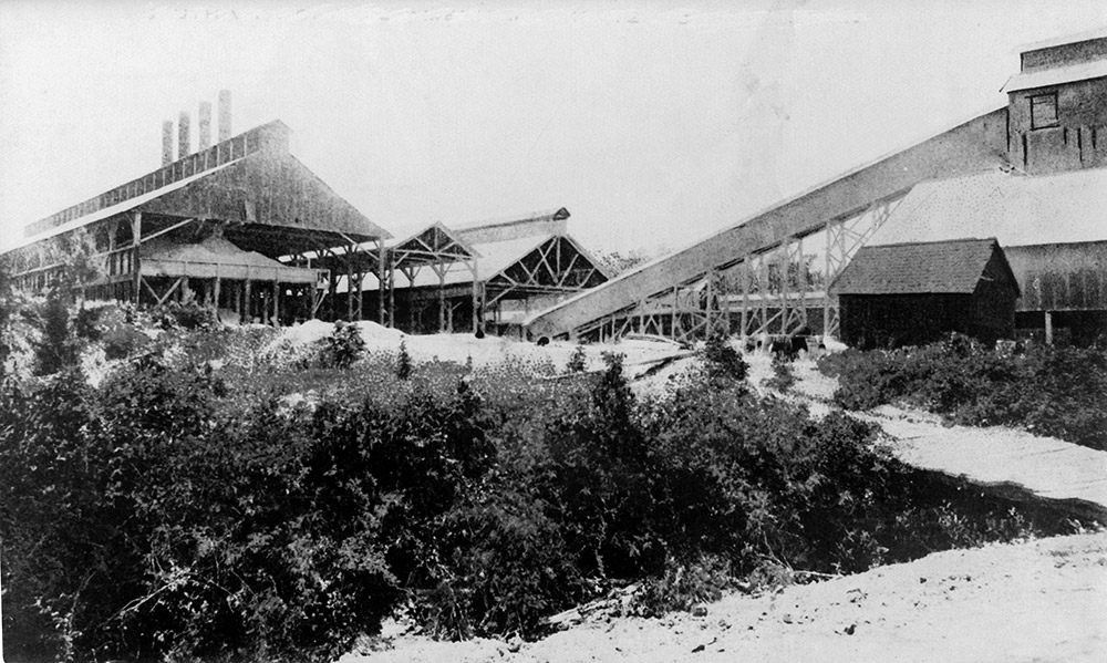 Several industrial wooden buildings with smokestacks