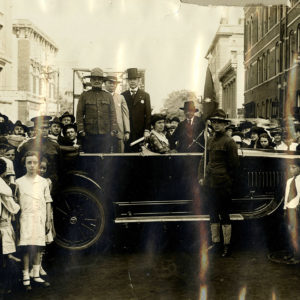 White men standing in open car amid large crowd of people