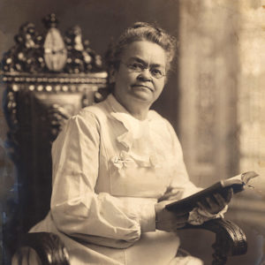 Seated white woman in white dress holding book