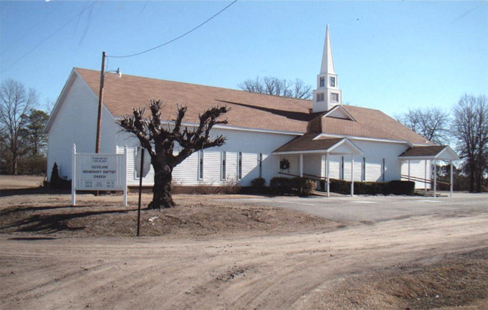 Single story white wooden church building with a steeple