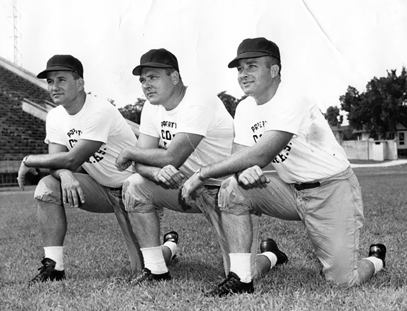Three white man in caps and white t-shirts kneeling