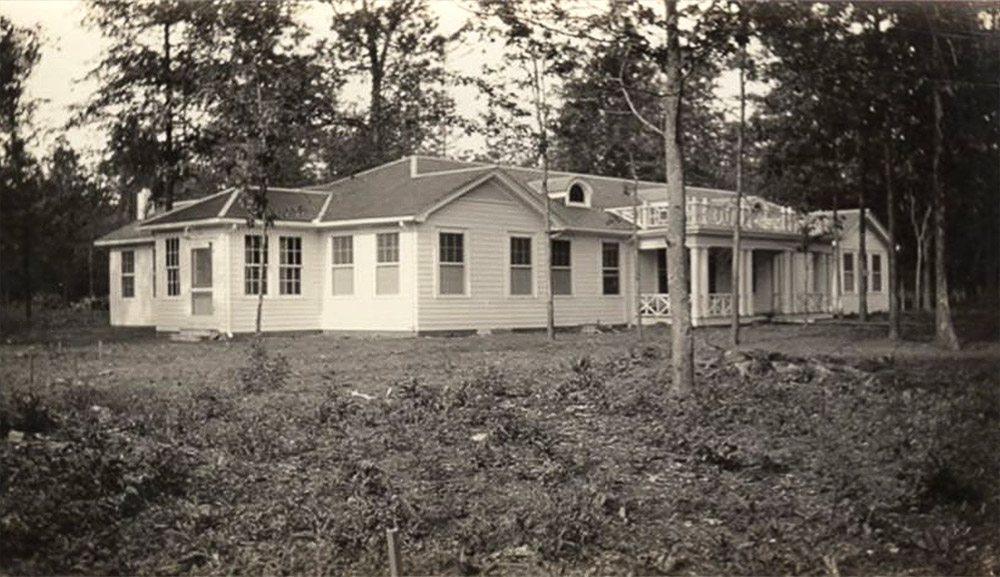 Single story white building surrounded by trees