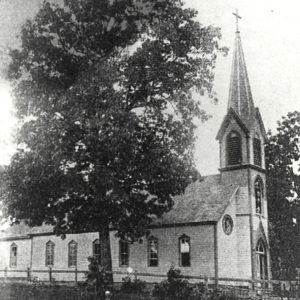 Wooden church building with large spire with cross on top