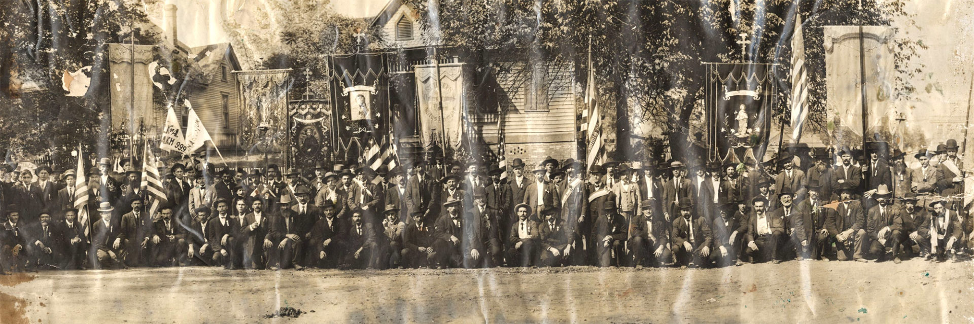 Large group of men in suits and hats posing for photo in front of flags