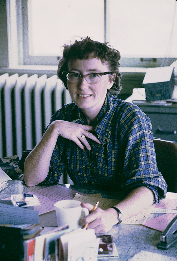White woman wearing glasses seated at desk