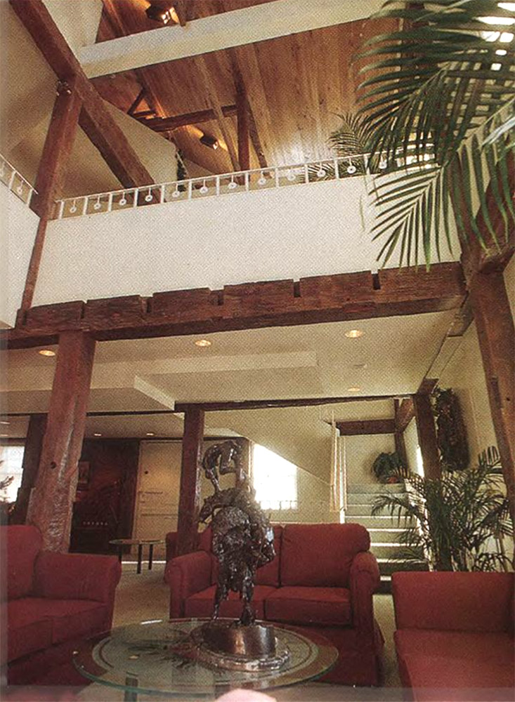 Lobby at the interior of a multistory building with ferns and red couches