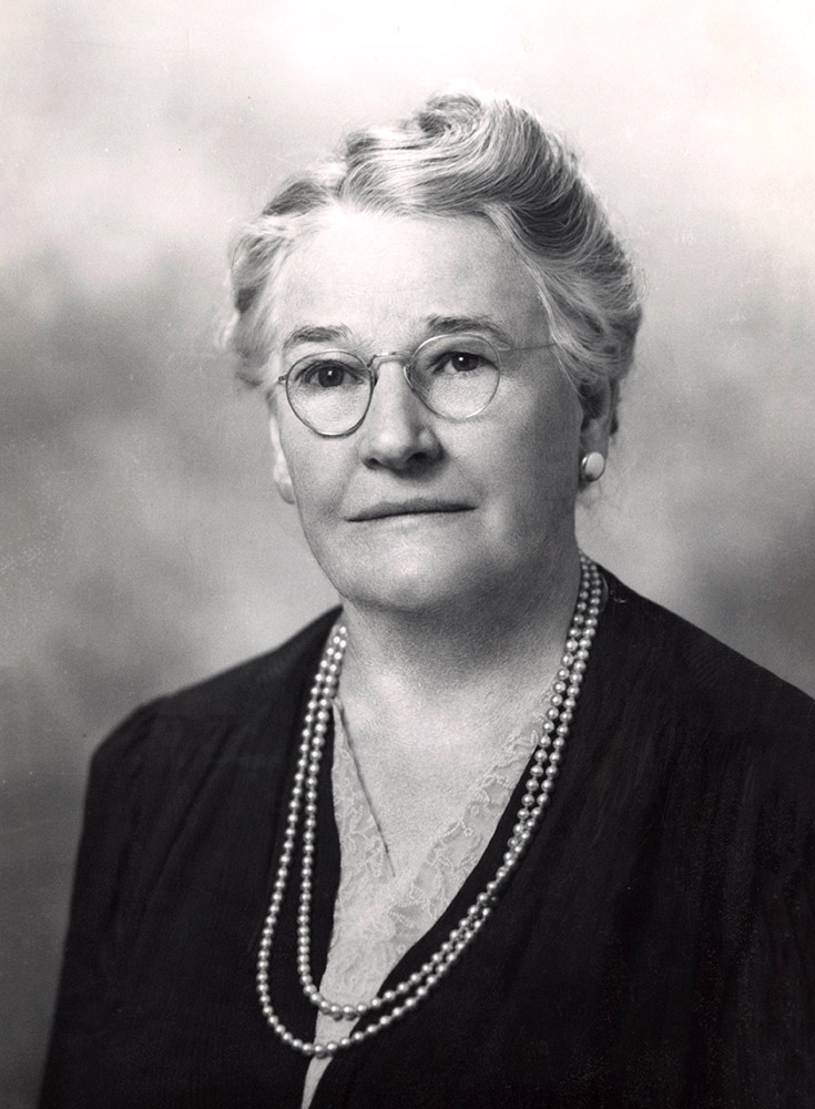 portrait of white woman wearing glasses and a string of pearls