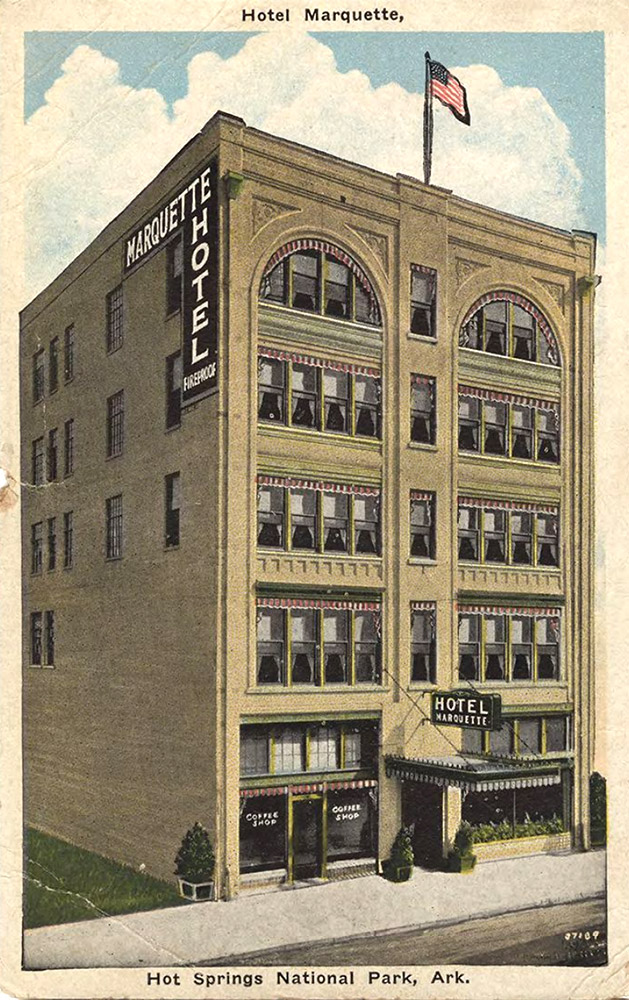 Multistory tan brick building with a sign saying "Marquette Hotel"