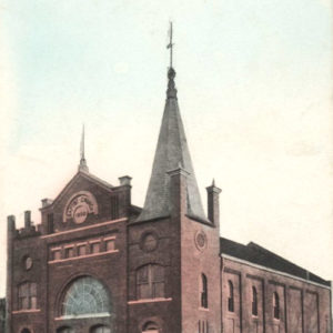 Large brick multistory church building with arched doorways and a spire