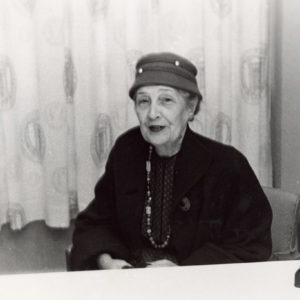 older white woman wearing hat sitting at desk