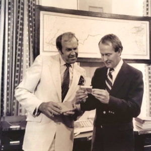 Two white men in suits looking at an object